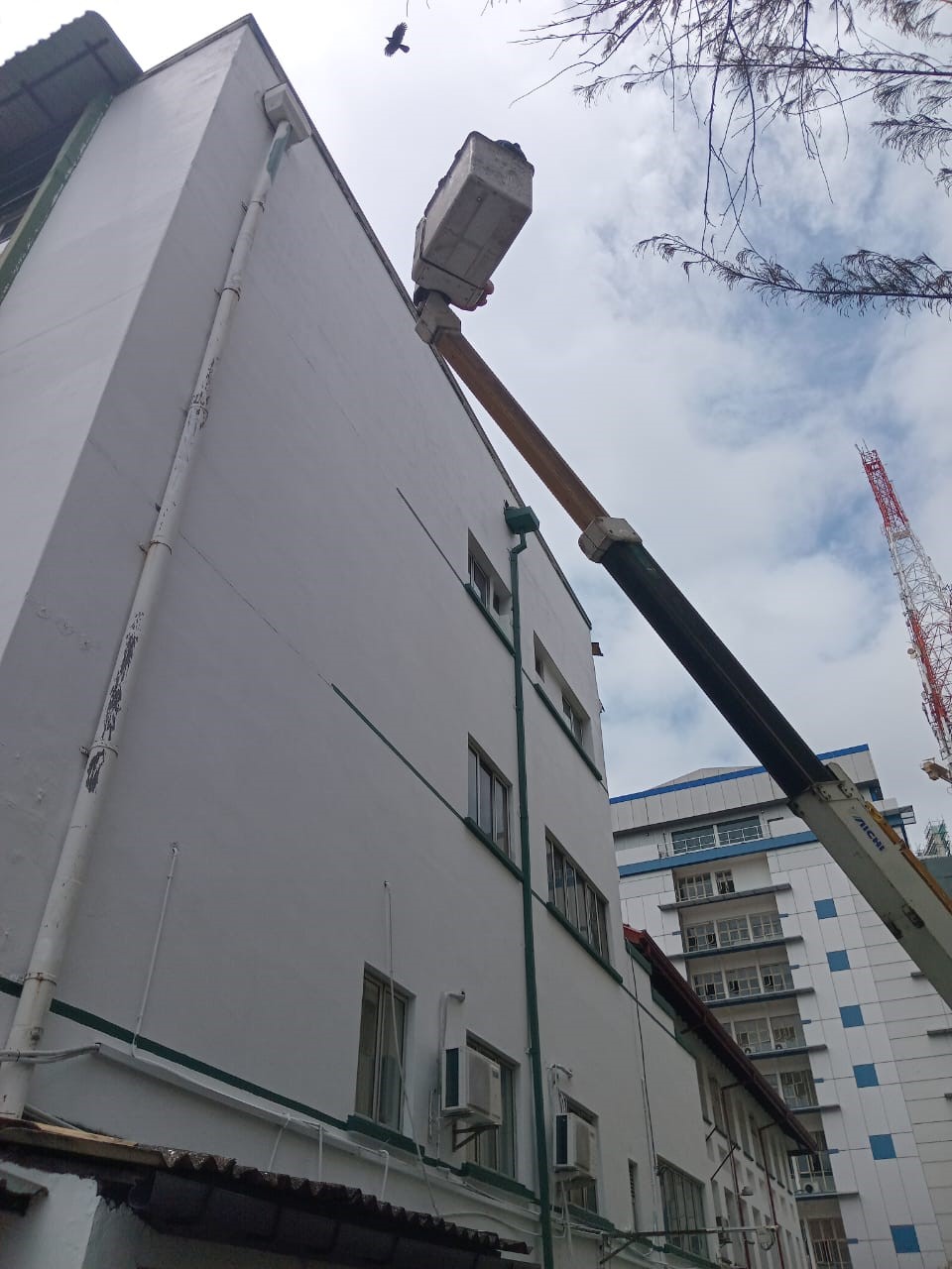 Exterior wall painting being done from a crane lift