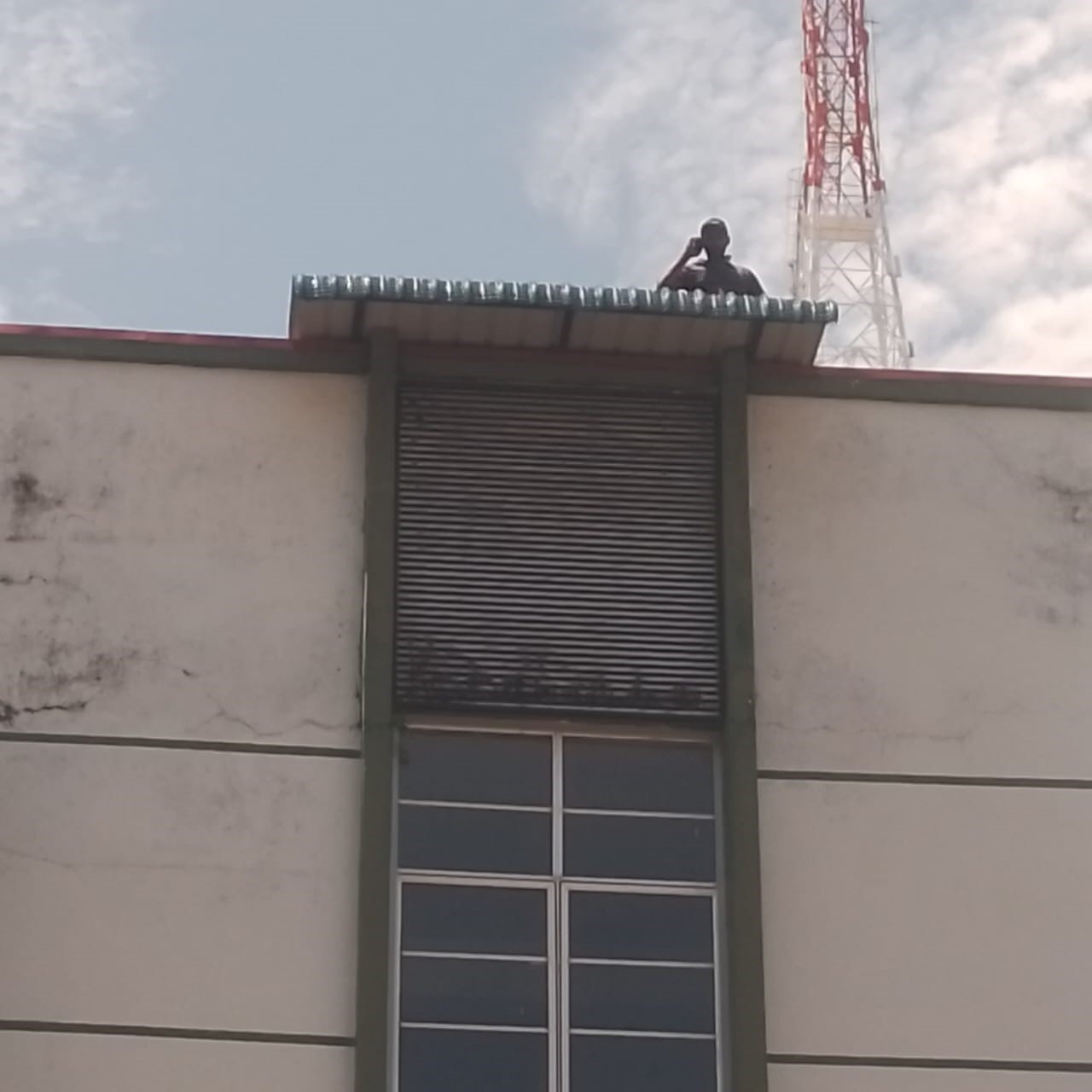Worker on the roof edge above a window shutter