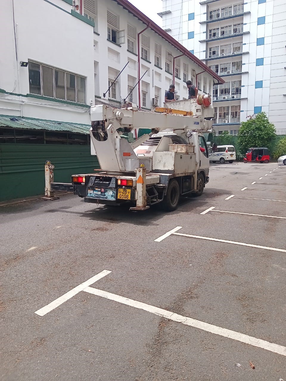Crane truck in the parking area with workers in the lift